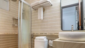 A modern bathroom with a glass-enclosed shower, a white toilet, a sink with a mirror, and a towel rack. - Samann Blue (Hulhumale)