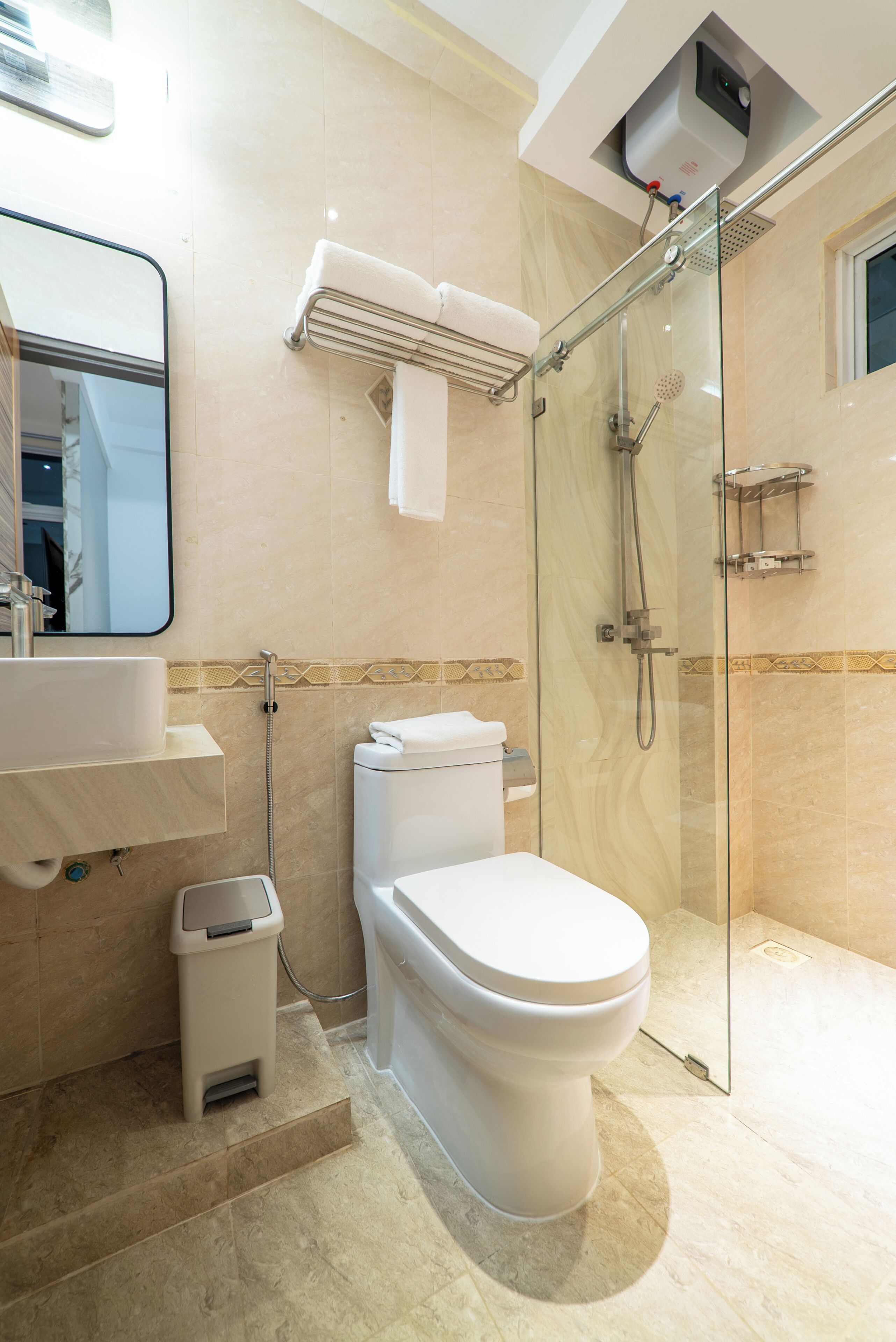 A modern bathroom with a glass-enclosed shower, a toilet, a sink, and a towel rack.