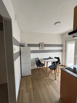 A compact kitchen with a refrigerator, a dining table with chairs, and a picture on the wall. - ApartmentMeerZeit with sea view Tribunj (Tribunj)