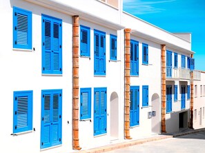 A white building with blue shutters and columns. - Cala Del Porto 2-room-apartment 3P (Marettimo)