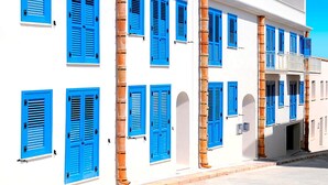 A white building with blue shutters and columns. - Cala Del Porto 2-room-apartment 3P (Marettimo)