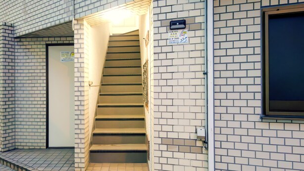 En trappe fører op til en dør med et skilt, der angiver en hotelindgang.