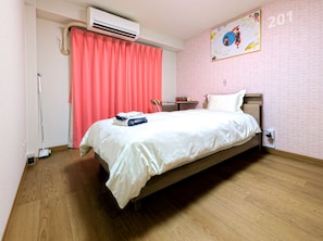 A hotel room with a bed, a desk, an air conditioner, a curtain, and a wall with a number. - Ikebukuro 5 Min by Train | 15㎡ for 1 | Kitchen, Free Laundry | Fast Wi-Fi (板橋区弥生町)