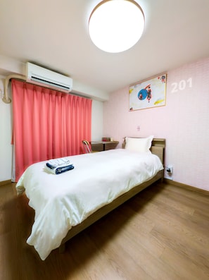 A hotel room with a bed, a desk, an air conditioning unit, a curtain, and a wall number. - Ikebukuro 5 Min by Train | 15㎡ for 1 | Kitchen, Free Laundry | Fast Wi-Fi (板橋区弥生町)
