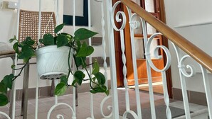 Eine Treppe mit weißen Metallgeländern und einem hölzernen Geländer, die zu einem Raum mit Fenster und Tür führt.