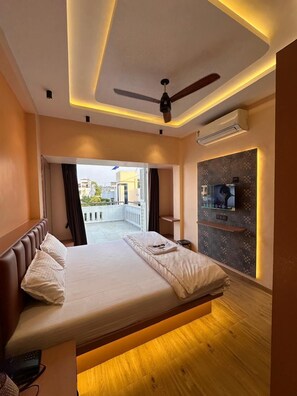 Une chambre d’hôtel moderne équipée d’un lit, d’un ventilateur de plafond, de la climatisation, d’une télévision et d’un balcon avec vue.