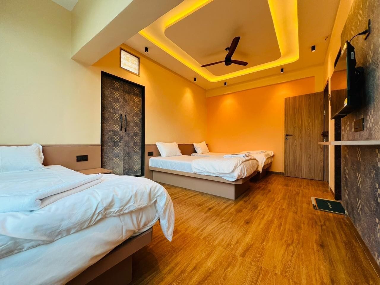 A hotel room with two beds, a ceiling fan, and a wooden floor.