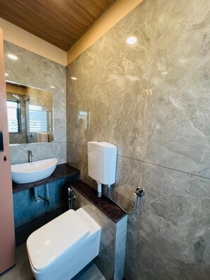 Une salle de bain moderne avec un mur en marbre, un lavabo, des toilettes et un sèche-mains.
