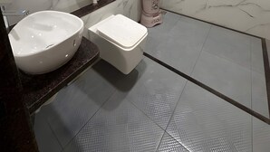 Ein Badezimmer mit Marmorwand, Waschbecken, Toilette, Dusche und Fenster.