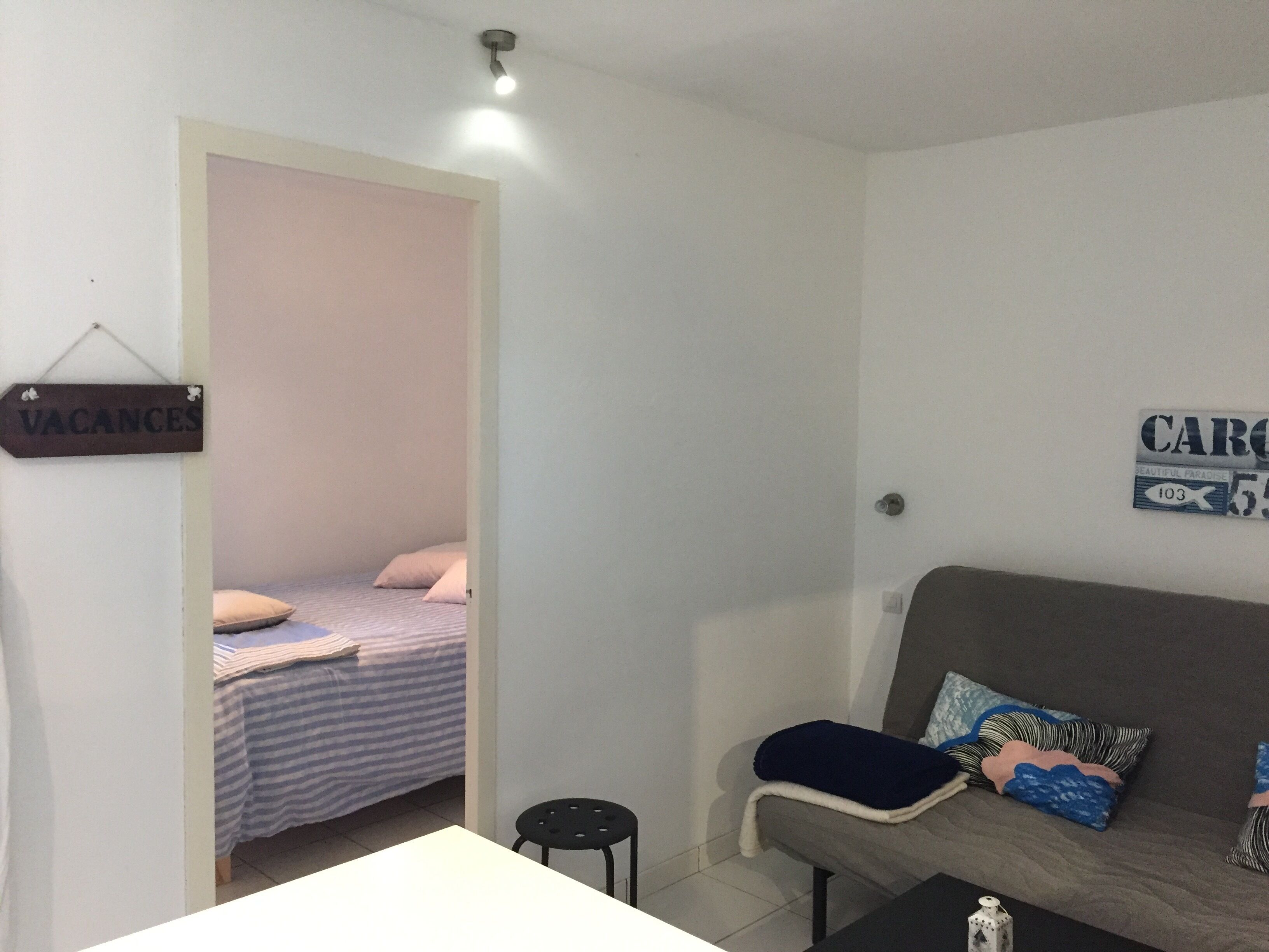 A room with a bed, a sofa, a small table, and a sign indicating vacancies.