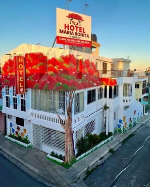 Ein Gebäude mit einem Schild für 'HOTEL MARIA BONITA HIGUÉY' und einem Baum davor.