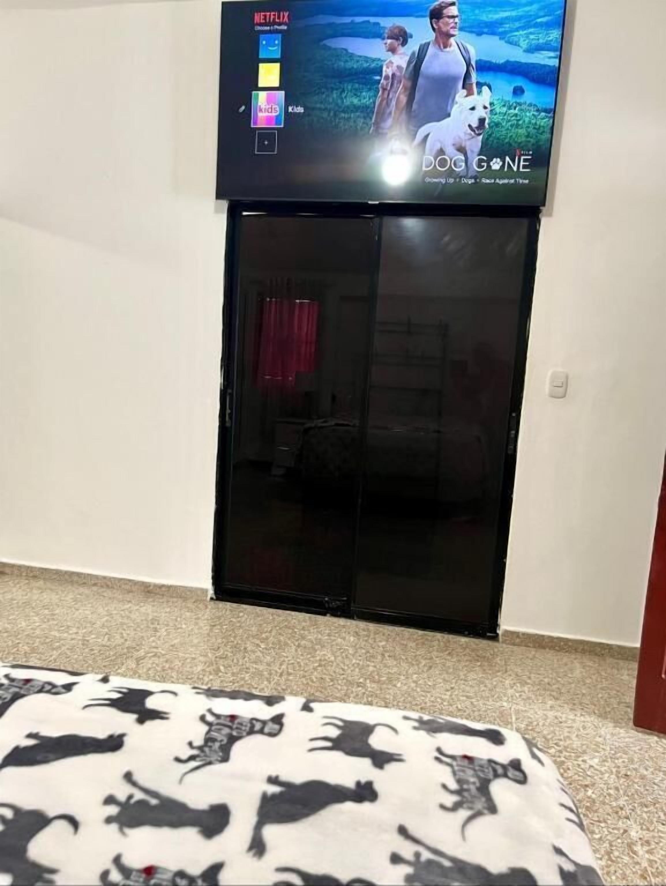 A room with a bed, a television mounted on the wall, and a door.
