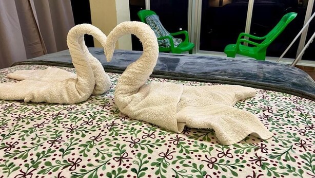 A bed with a floral bedspread and two swan-shaped towels. - Hotel María Bonita Higüey, Apartments (Higüey)