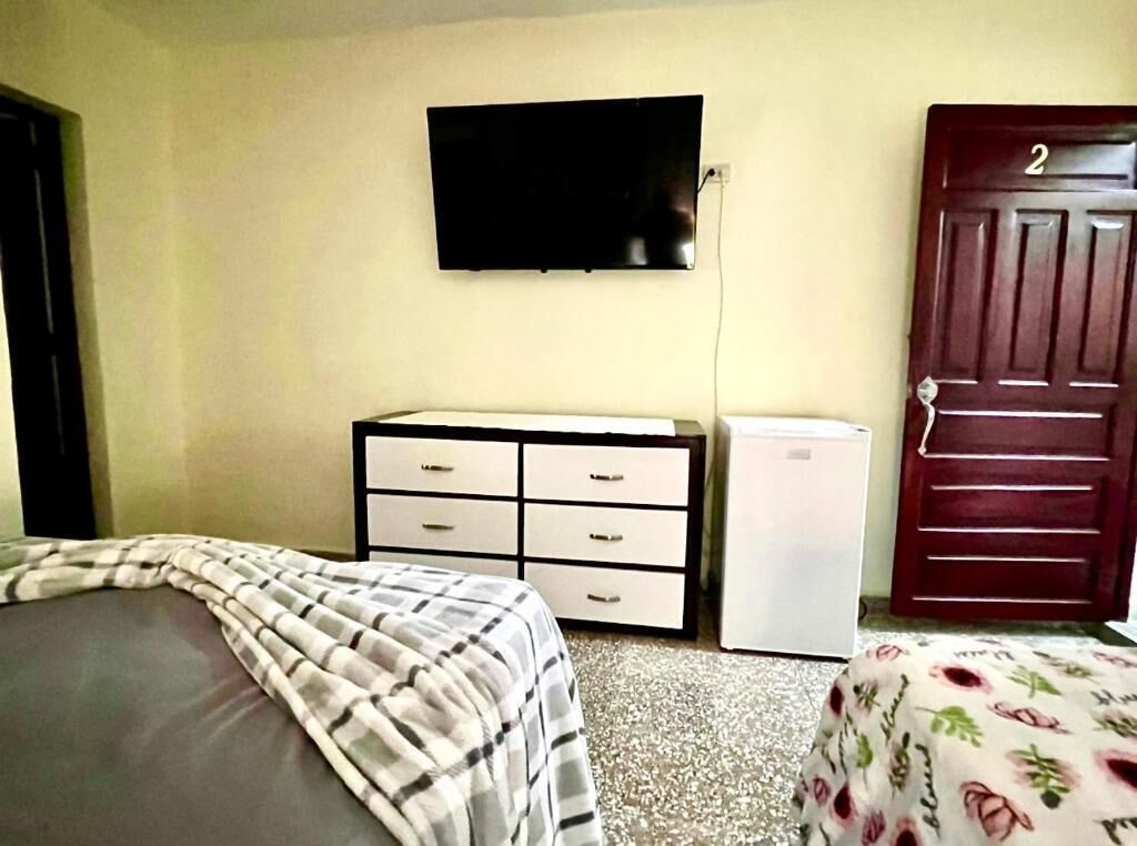 A bedroom with a bed, a dresser, a television, and a door.