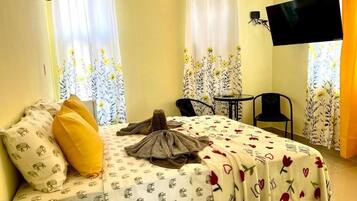 A hotel room with a bed, a chair, a small table, and a TV.