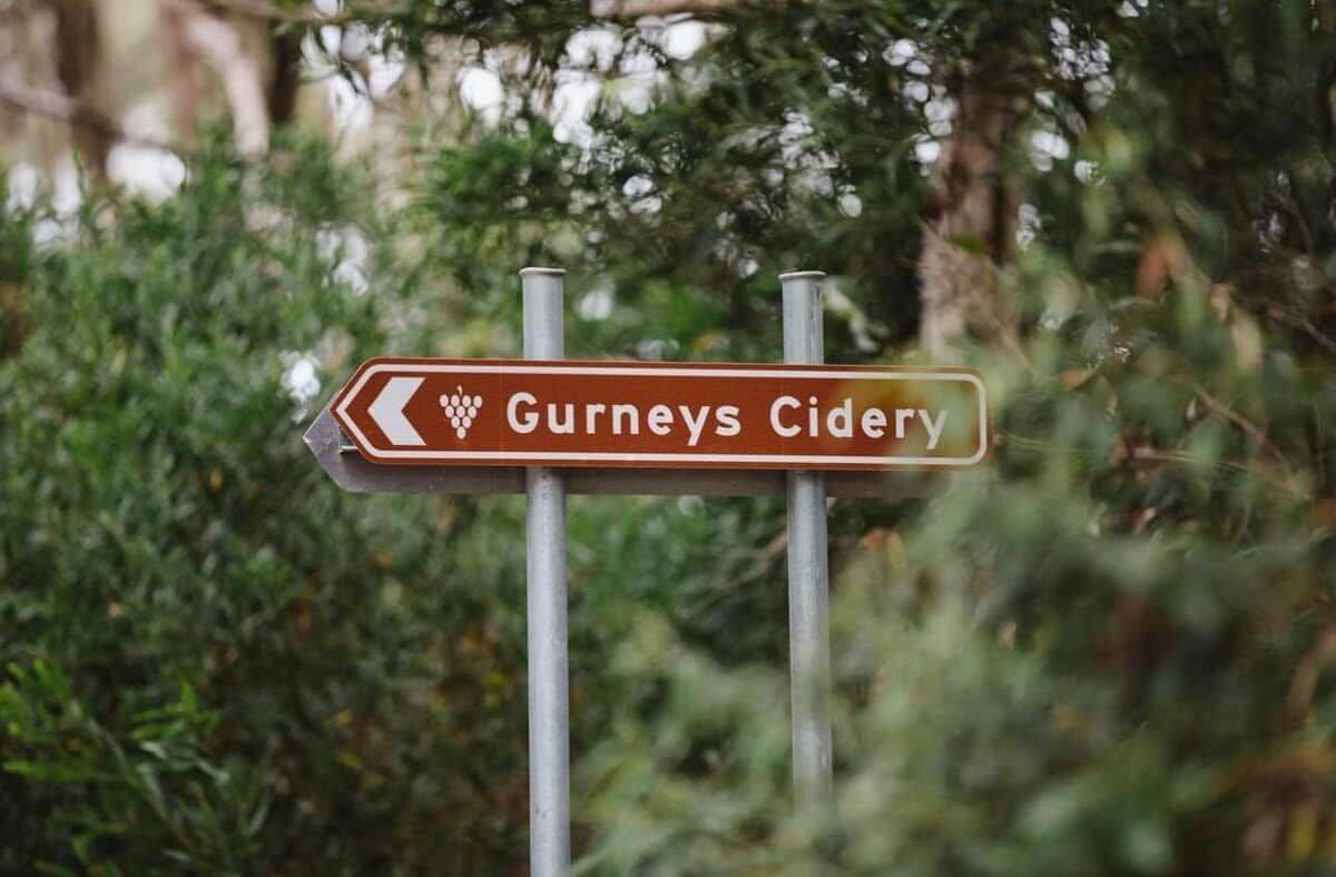 A directional sign for Gurneys Cider pointing to the left.