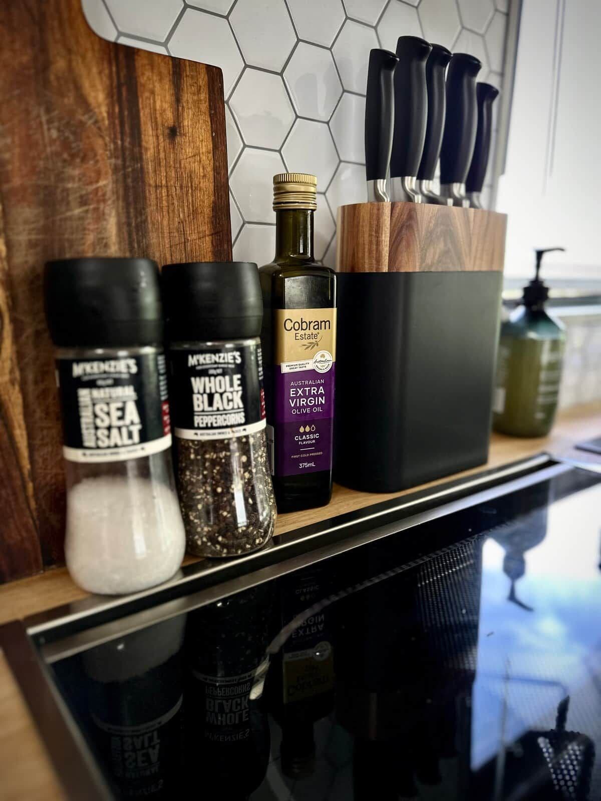 A kitchen counter with various condiments and a bottle of olive oil.