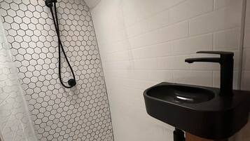 A bathroom with a shower, a sink, and a toilet.