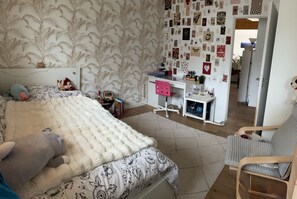 Ein Schlafzimmer mit Bett, Schreibtisch, Stuhl und einer Bilderwand.