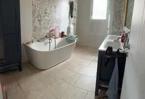 Ein Badezimmer mit einer freistehenden Badewanne, einem Waschtisch mit Spiegel und einem Handtuchhalter.