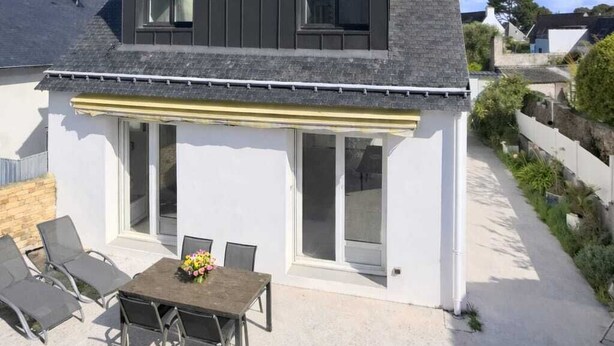 Moderni, kaksikerroksinen talo, jossa on patio, satelliittiantenni ja pieni puutarha.