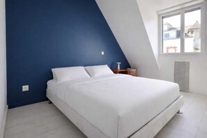 A bedroom with a bed, a nightstand, a window, and a radiator. - Cosy house 6 pers near beaches, south facing (Quiberon)