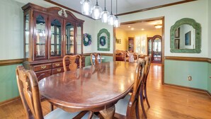 Comedor con una gran mesa de madera, sillas, un aparador y luces colgantes.