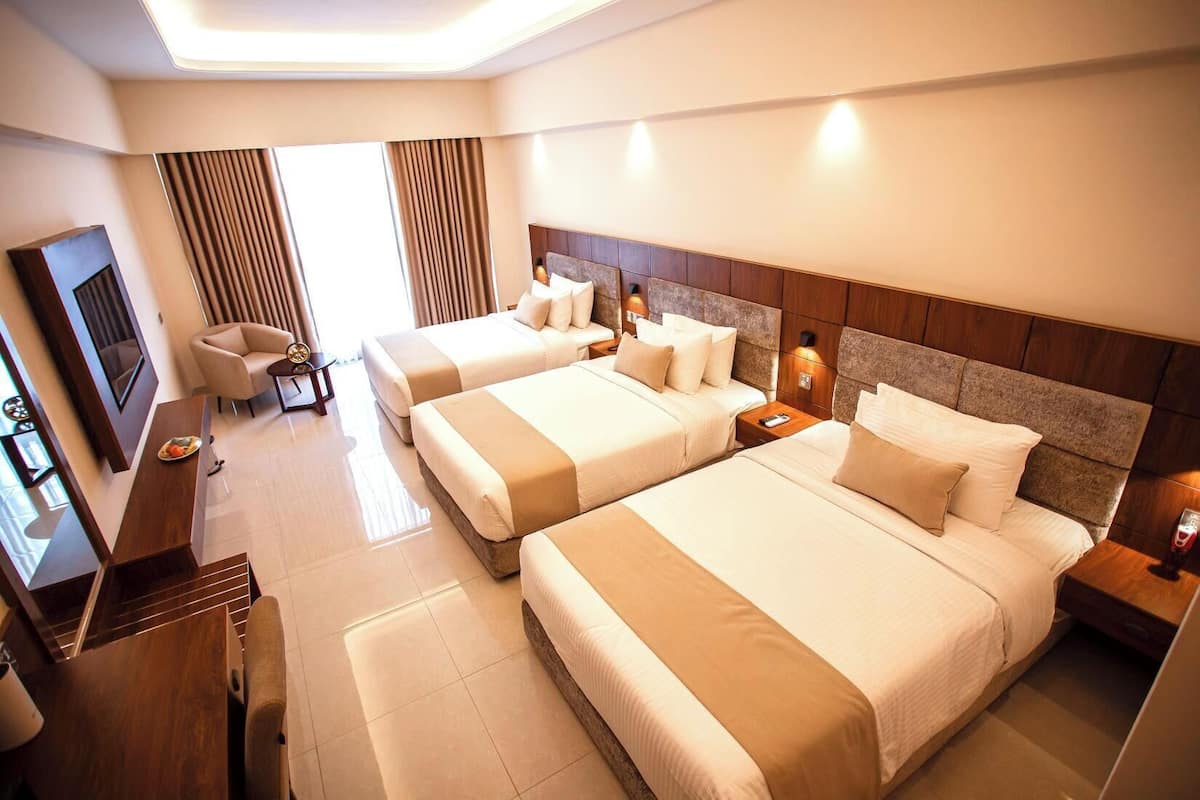 A hotel room with two beds, a TV, a desk, and a chair.