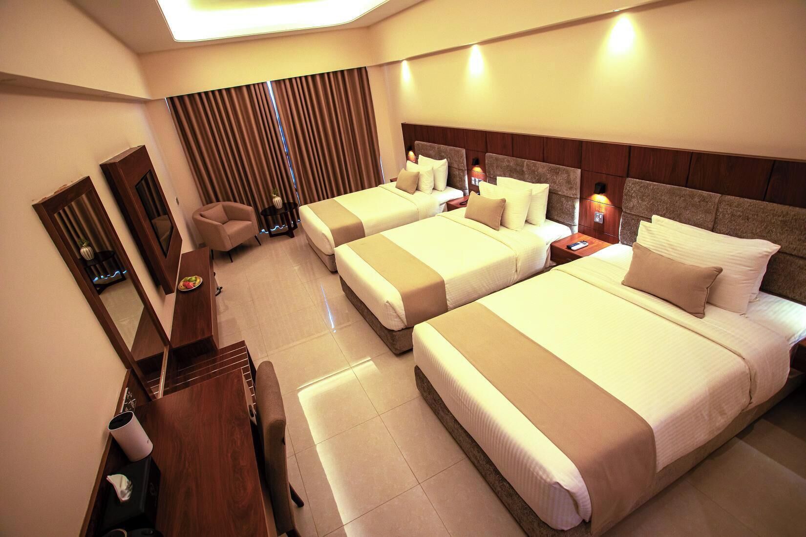 A hotel room with a large bed, a smaller bed, a desk, and a chair.