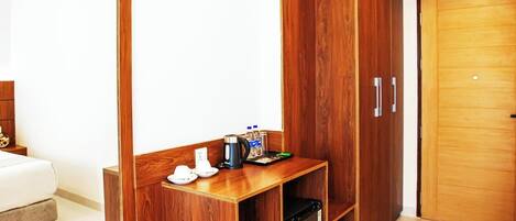A modern hotel room with a wooden bench, a wardrobe, a mirror, and a bed.