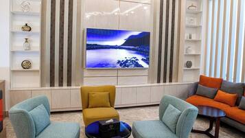 A modern living room with a flat-screen TV, two armchairs, a coffee table, and a sofa.