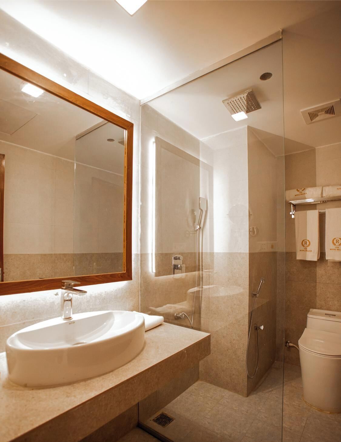 A modern bathroom with a large mirror, a sink, a shower, and a toilet.