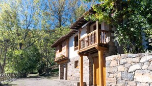 Ein rustikales Steinhaus mit Balkon, umgeben von Bäumen.