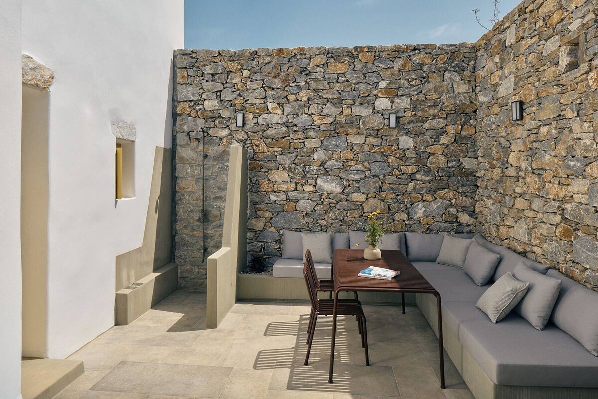 A modern outdoor patio with a stone wall, a sofa, and a table.