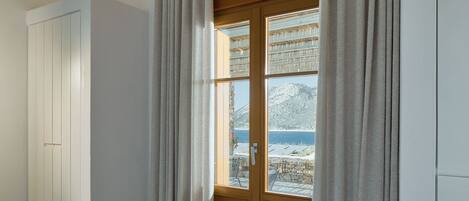 Una habitación con puerta de madera, paredes blancas y vistas a un paisaje montañoso.