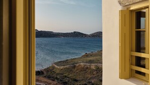 A coastal view through a window with a stone ledge and a yellow frame. - Amorgina (Amorgos)