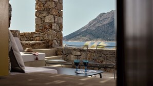 A stone pillar, a white sofa, and a table with two glasses. - Amorgina (Amorgos)