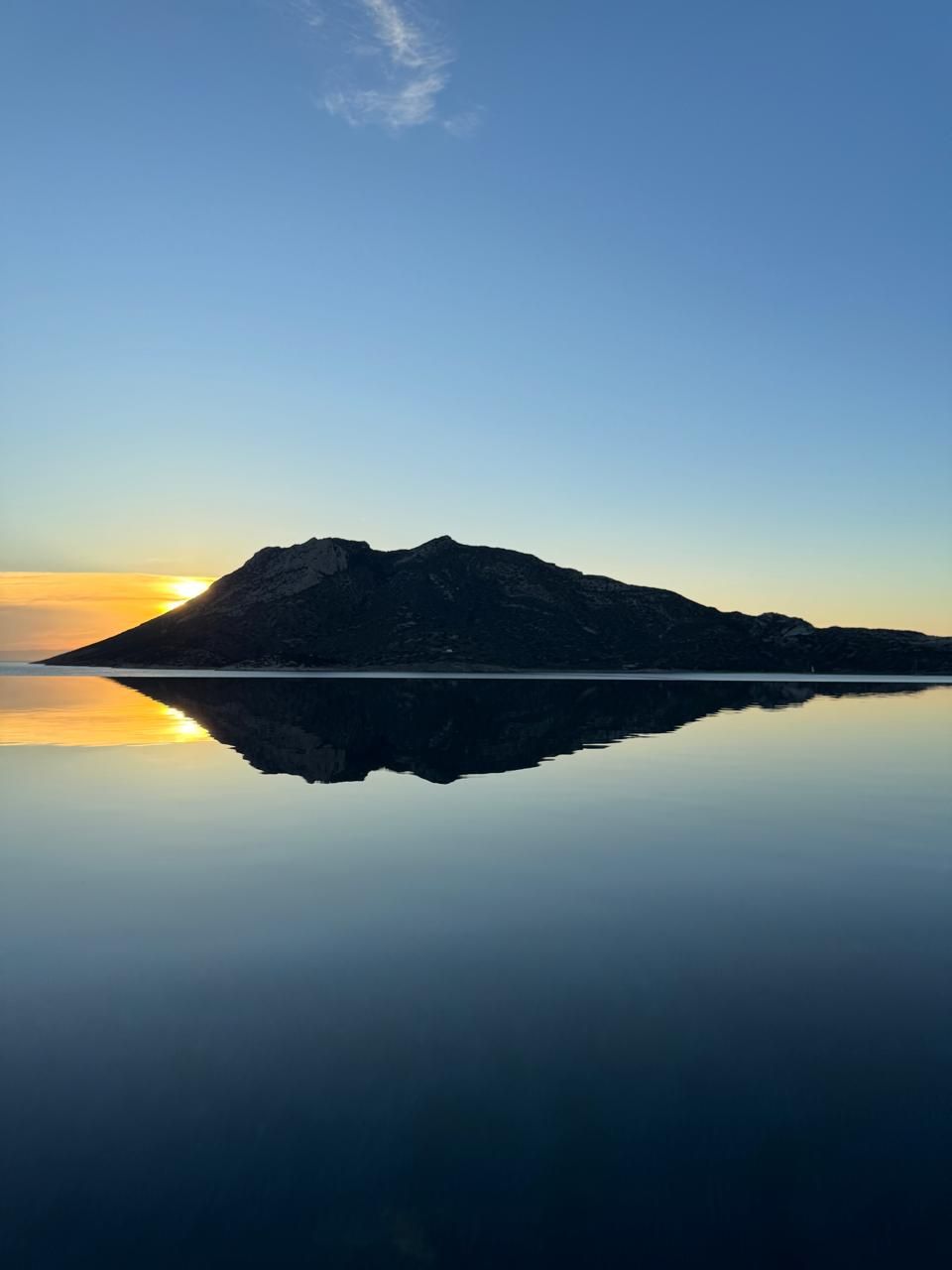 A mountain reflected in calm water with a clear sky.