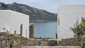 A coastal view with stone walls and a clear view of the sea and mountains. - Amorgina (Amorgos)