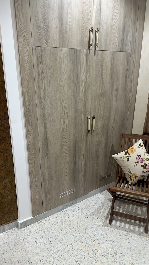 Un armario de dos puertas y un banco con cojín floral.