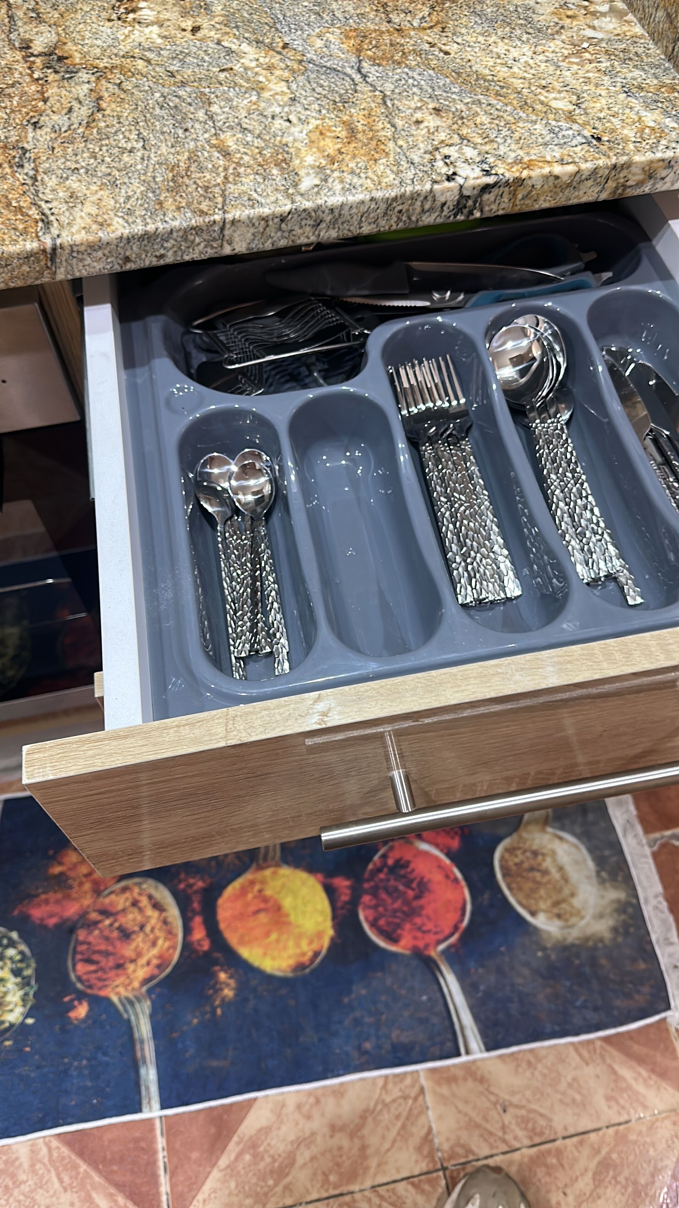 Un tiroir contenant un ensemble de couverts, notamment une cuillère, une fourchette et un couteau.