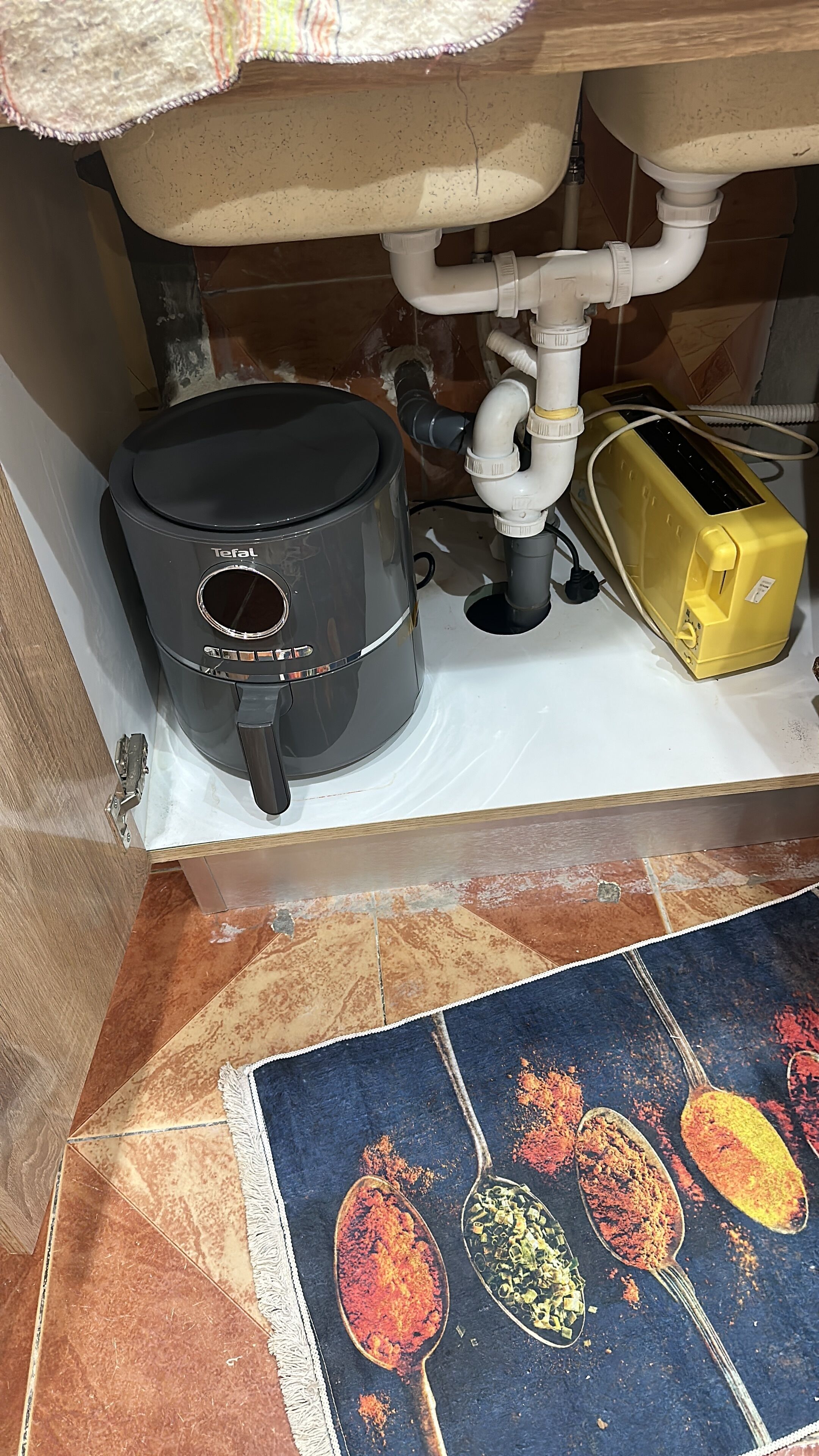 Ett kök med en kaffebryggare, en gul brödrost och en diskho under ett skåp.