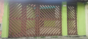A large metal gate with diagonal slats, a green wall, and a number '228' on the right. - Cozy Grandma's Little House - 200m from the Sea + Pool + Pet-Friendly (Itanhaém)