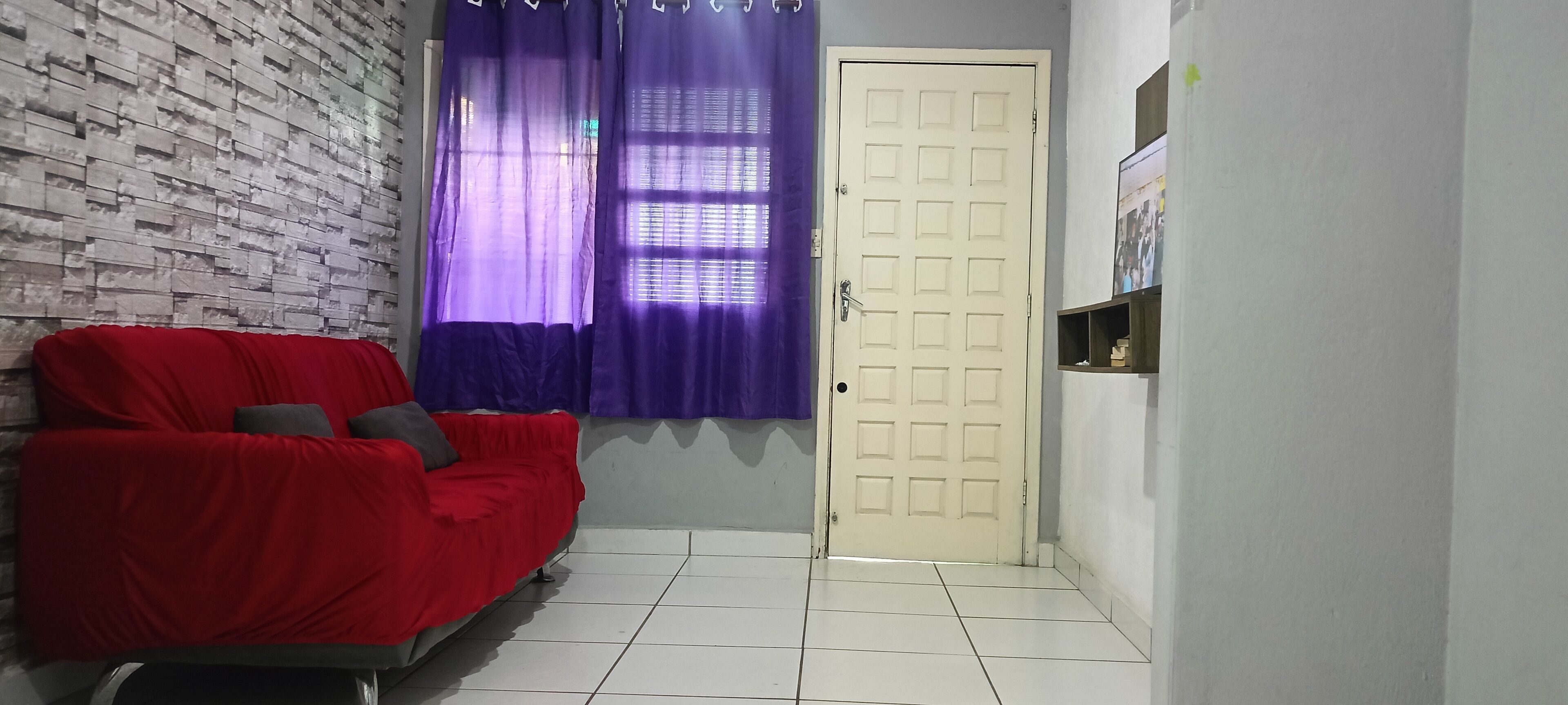 A room with a red sofa, a white door, and a purple curtain.