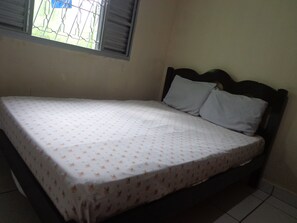 A single bed with a floral bedspread in a room with a window and a plain wall. - Cozy Grandma's Little House - 200m from the Sea + Pool + Pet-Friendly (Itanhaém)