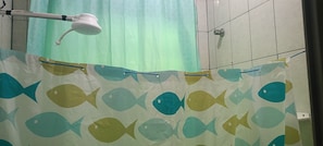 A bathroom with a shower curtain featuring a fish pattern, a visible showerhead, and tiled walls. - Cozy Grandma's Little House - 200m from the Sea + Pool + Pet-Friendly (Itanhaém)
