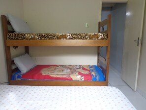 A bunk bed with a patterned top bunk and a red bottom bunk. - Cozy Grandma's Little House - 200m from the Sea + Pool + Pet-Friendly (Itanhaém)