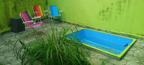 A small outdoor area with a blue pool, green walls, and colorful chairs. - Cozy Grandma's Little House - 200m from the Sea + Pool + Pet-Friendly (Itanhaém)