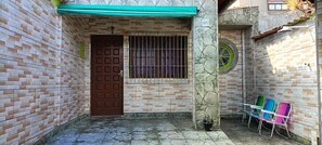 A narrow alleyway with a tiled floor, a brown door, a barred window, and a green awning. - Cozy Grandma's Little House - 200m from the Sea + Pool + Pet-Friendly (Itanhaém)