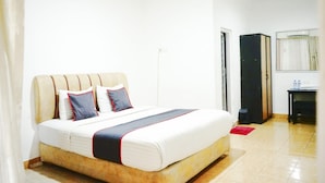 Una habitación de hotel con una cama, un escritorio, un armario y un espejo.